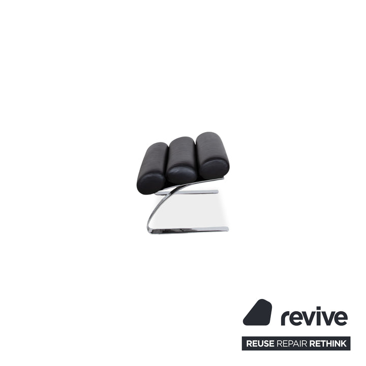 Fauteuil Cor Sinus en cuir chromé noir avec repose-pieds et bras articulés.